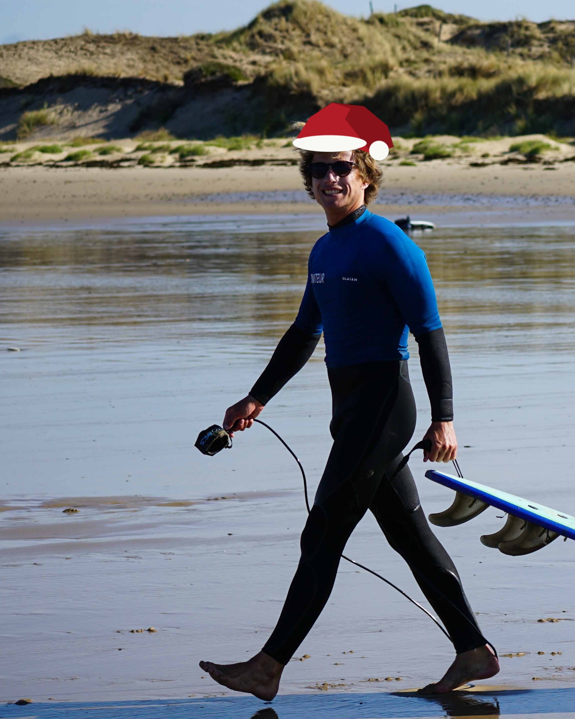 Un surfeur souriant sur la plage d'Hatainville, planche à la main